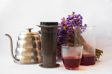 White background, strong, morning, specialty coffee brewed by an alternative method from gadget. Bouquet of field flowers and glassware.