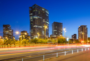 Fototapeta na wymiar Paisaje urbano de los edificios de la ciudad de Barcelona al anochecer con calle en primer termino y las luces de los coches.