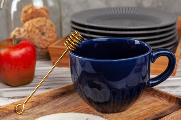 Still life photo of empty tea cup with honey spoon. Kitchen table close up