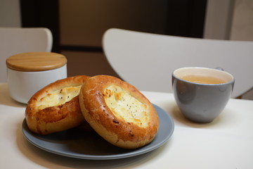 Mug with tea and cheesecakes on a plate. Gray dishes on a white table