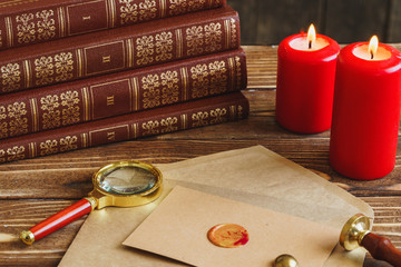 Letter with ground seal, magnifying glass and burning candles on wooden table