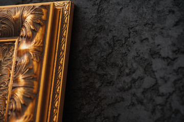 Beautiful golden frame on black wall with pattern close up