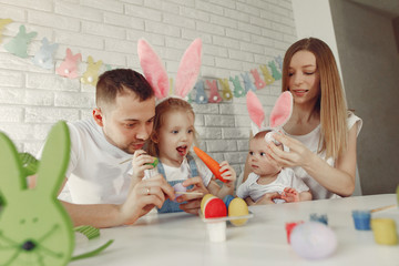 Obraz premium Parents and daughter paint eggs. Family in a kitchen. Preparing for Easter