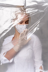 Obraz na płótnie Canvas Quarantined woman wears a protective mask. Quarantined woman breakthrough of oilcloth.