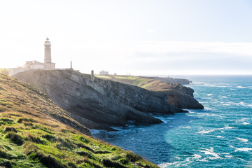 Fototapeta na wymiar Beautiful landscape of a lighthouse near the cliffs and the ocean on a blue winters day