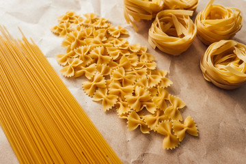 Varieties of Italian pasta. Spaghetti, farfalle and tagliatelle isolated on a white background, top...
