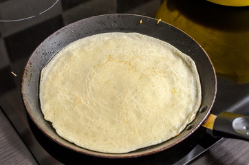 Culinary cook fries pancakes in a pan on an induction stove