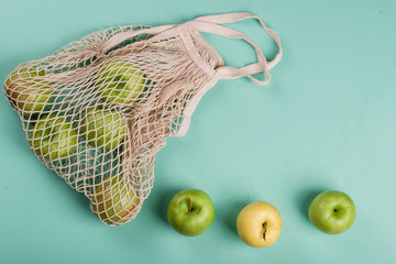 Ripe apples of different varieties in an eco bag on a light background.