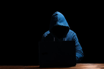A Hacker with laptop sits at a table and abstract binary code. Business life threat virtual programs.