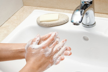 A Hands with soap are washed under the tap with water. Clean from infection and dirt and virus. At...