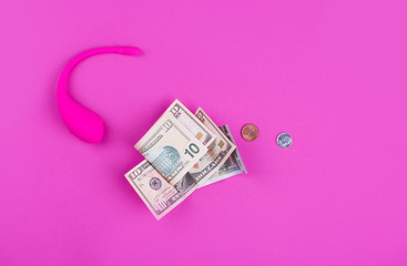 A female pink vibrator with money rests on a pink background .