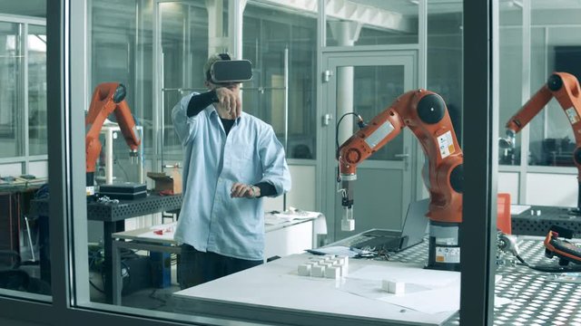 Male researcher wearing VR-glasses in a laboratory with a robot