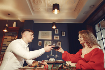 Couple in a restaurant. Lady in a red dress. Pair drinking a vine. Valentine's day.