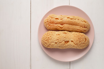 Eclair on the plate. Light pastel background. Dessert. concept, minimalism