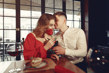 Couple in a restaurant. Lady in a red dress. Pair drinking a vine. Valentine's day.