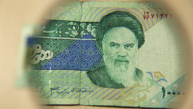 View a Ten thousand Iranian rials bill lying on a table with a magnifying glass. concept of business and finance. Obverse