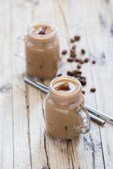 Iced coffee milk in a jar with a metal tube on a on a wooden background