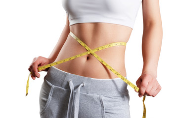 Close up of slim woman measuring her waist's size with tape measure.
