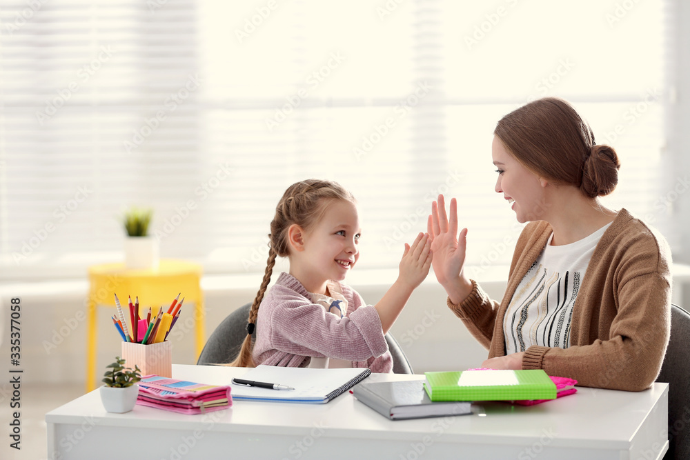 Canvas Prints Mother and daughter doing homework together at table indoors