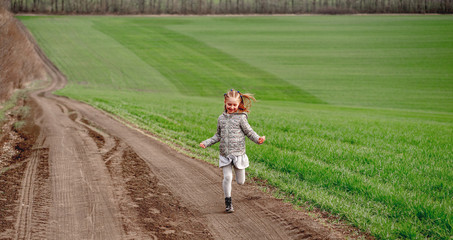 Little girl running on spring field