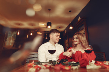 Couple in a restaurant. Lady in a red dress. Pair drinking a vine. Valentine's day.