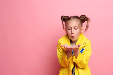 Pretty girl blowing on palms with hairstyle on pink background. empty space. pleasant feelings concept.