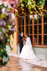 Fototapeta premium Beautiful wedding couple. Elegant bride dress and black stylish suit of the groom. Wedding photo session in a beautiful place