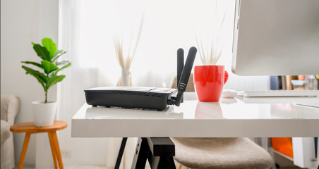 closeup of a wireless router on living room at home ofiice, equipment  for working from home, while in quarantine isolation during the Covid-19 health crisis.