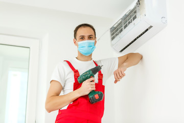 Fototapeta na wymiar Young worker installs air conditioner in the room with blue walls