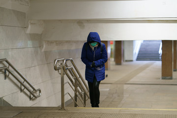 Young woman wear medical mask, headphones  and goes outdoors. Frontal view. Coronavirus Pandemic lifestyle of the big city