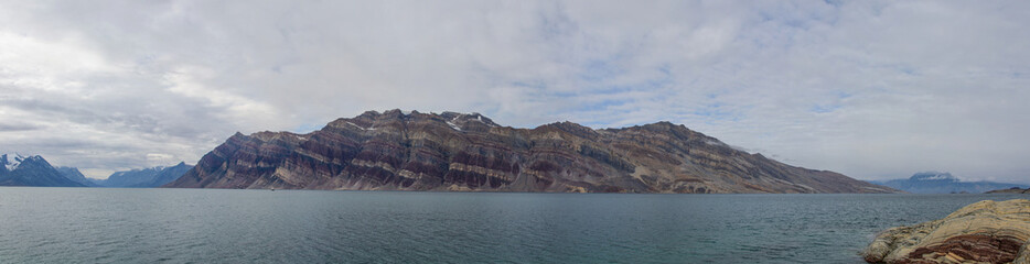 Greenland landscape with beautiful coloured mountains and iceberg.