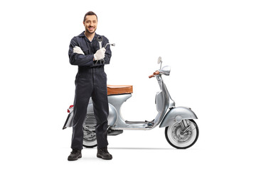 Motorcycle mechanic holding a wrench and standing next to a scooter