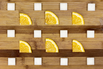 Tea concept. Pieces of lemon and sugar cubes on the wooden table in minimalistic style. View from above.
