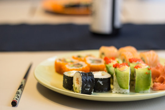 Sushi maki close-up on a green plate in warm colors with a blurred background.