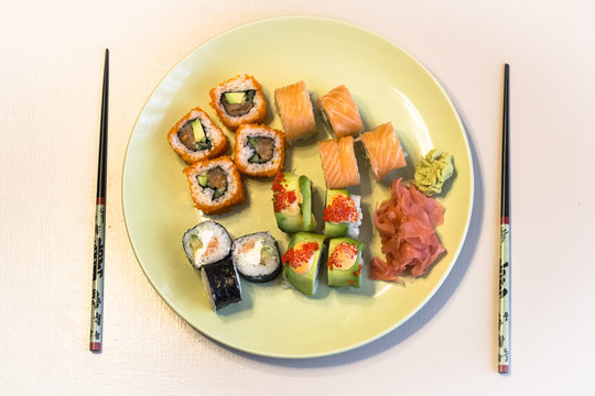 Green plate with a set of sushi maki in warm colors.