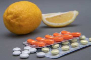 White and red tablets on a gray background and lemon. Concept: coronavirus, flu, disease, quarantine, covid-19