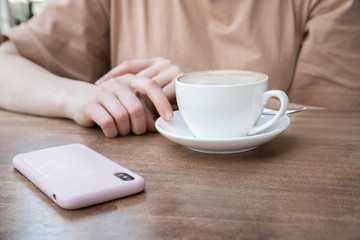 On the table a woman's hand, a Cup of coffee and phone. Mock up. Cooking, food delivery, cafe, restaurant, cheese Factory, cheese tasting