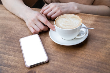 On the table a woman's hand, a Cup of coffee and phone. Mock up. Cooking, food delivery, cafe, restaurant, cheese Factory, cheese tasting