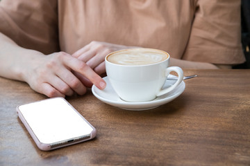 On the table a woman's hand, a Cup of coffee and phone. Mock up. Cooking, food delivery, cafe, restaurant, cheese Factory, cheese tasting