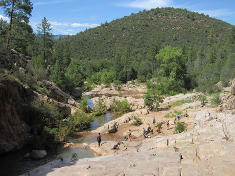 View over the Ellison Creek waterfall with unrecognizable tourists and locals below on the Water Wheel Falls hiking trail in Payson, Arizona