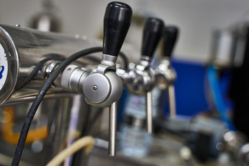Fototapeta na wymiar Metallic taps with rubber handles in a row connected to machines in a brewery