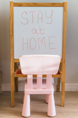 The inscription "stay home" written on the blackboard against the background of the interior of the kids room