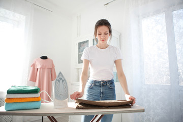 Woman Ironing Clothes On Ironing Board At Home. Young Smiling Woman Ironing Clothes On Ironing...