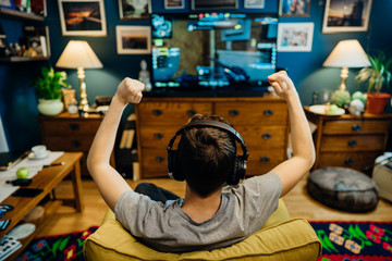 Young professional esport gamer with headphones playing and winning competitive internet MMORPG cyber championship in first person shooter strategy online video game on high end computer gaming rig