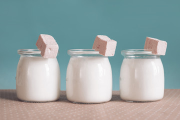 three glass jars with yogurt and pink marshmallow