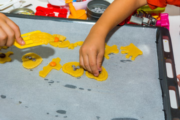 Young children playing with coockie dough, making cookies with models.