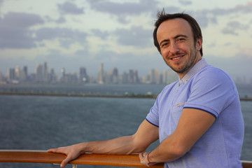 Handsome man aboard a cruise ship. Portrait of a smiling man on a background of a big city.