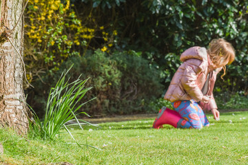 A girl playing outside picking flowers in a garden while at home