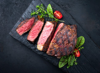 Barbecue dry aged wagyu entrecote beef steak with lettuce and tomatoes as top view on an old...