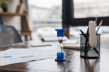 Hourglass near pen holder on table in office